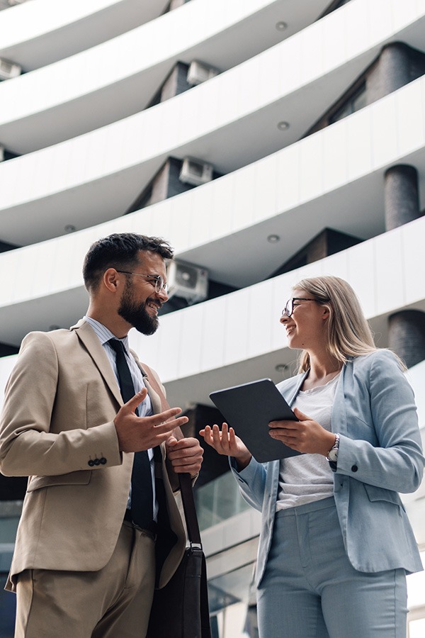 Zwei Geschäftspartner im Gespräch vor modernem Bürogebäude